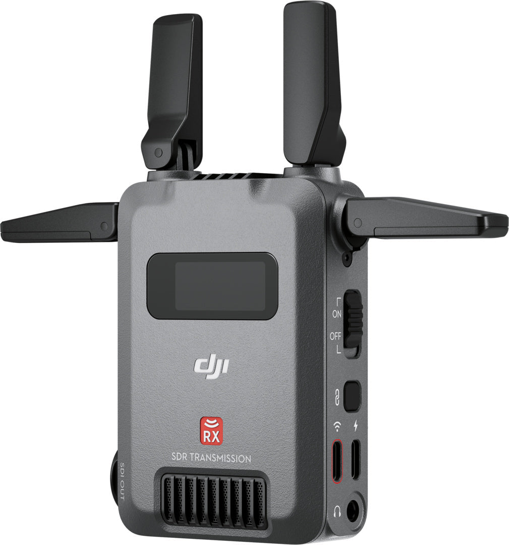 Ein grauer DJI RX SDR Übertragungsempfänger mit zwei Antennen, einem kleinen Bildschirm, mehreren Anschlüssen und Tasten an der Seite zur Steuerung und Konnektivität.