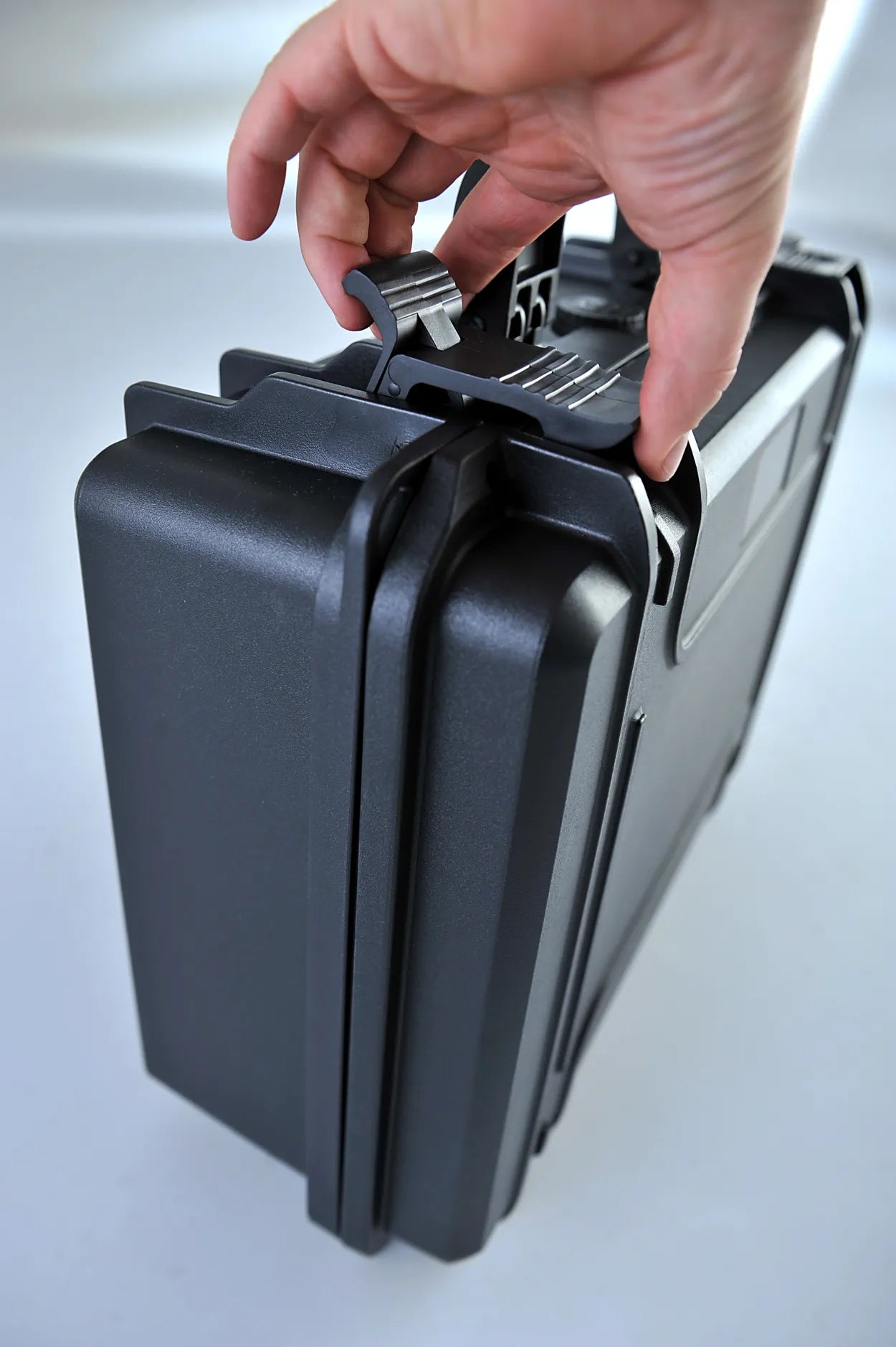 Eine Hand entriegelt den TomCase Mavic 3 (M3) Enterprise Koffer XT465 – Ready to Fly Version, einen robusten, wasserdichten Koffer für DJI Mavic 3 Enterprise, vor einem schlichten hellen Hintergrund.