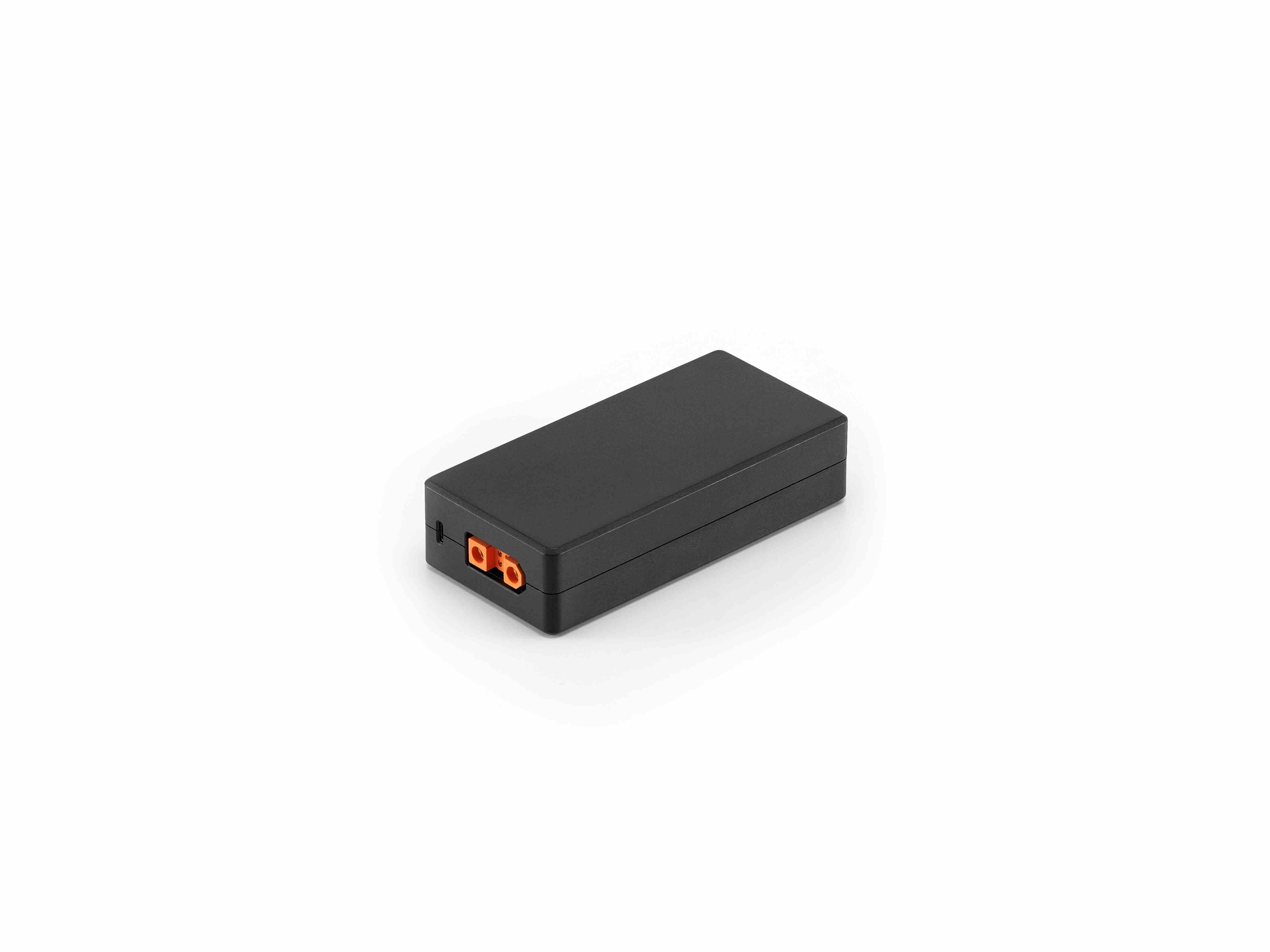 Das DJI Enterprise Ladegerät - Netzteil CDX230-240 für DJI Matrice 4D/4TD ist ein rechteckiges schwarzes Gerät mit einem kleinen orange-schwarzen Anschluss, der intelligenten Schutz bietet. Auf weißem Hintergrund dargestellt.