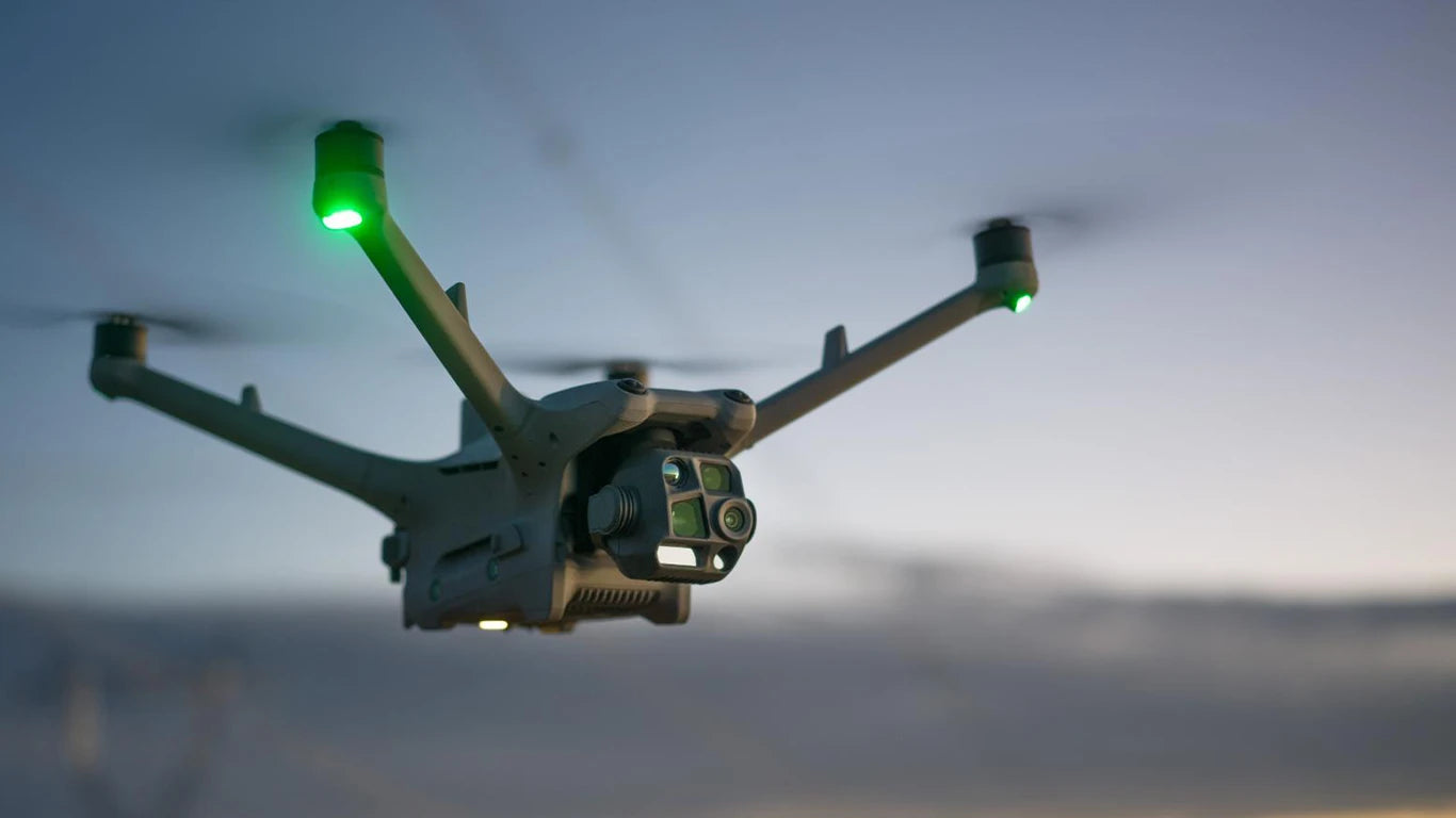 Eine Nahaufnahme der DJI Enterprise Matrice 4TD Stand-Alone Combo (M4TD) Allwetterdrohne mit IP55-Schutz, grüne Lichter leuchten beim Flug in der Dämmerung, während sie Wärmebildanalysen gegen den verschwommenen Himmel durchführt.