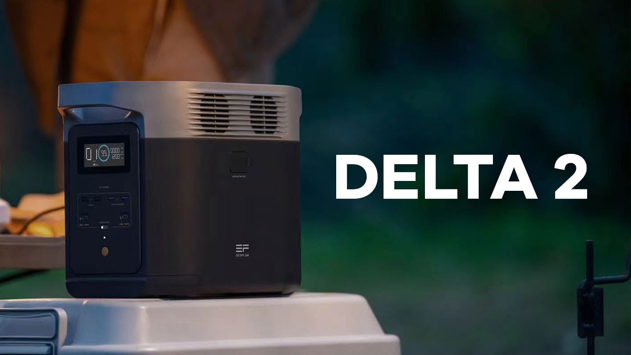 Eine EcoFlow Power Station Delta 2 (1000 Wh) mit Digitalanzeige und Steckdosen steht auf einem Tisch im Freien. Der Schriftzug „DELTA 2“ hebt den LiFePO4-Akku hervor. Im Hintergrund ist ein verschwommenes Grün zu sehen.