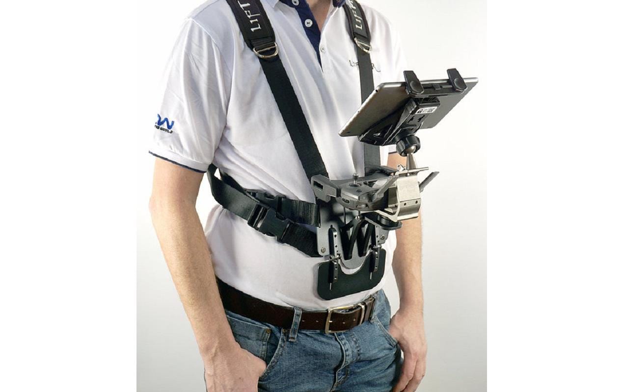 Eine Person in einem weißen Poloshirt mit Logo und Blue Jeans trägt den LifThor Sendertragegurt StrapThor PRO. Dieser von LifThor entwickelte Gurt verfügt über verstellbare Gurte und einen Metallrahmen zur Unterstützung und sorgt so für Komfort und Mobilität beim Halten eines Tablets.