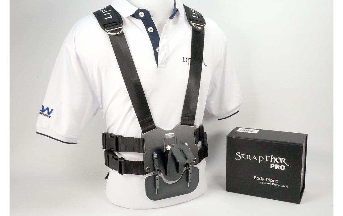 Eine Schaufensterpuppe in einem weißen Poloshirt präsentiert den schwarzen LifThor Lifter-Gurt mit Metall- und Kunststoffkomponenten. Daneben präsentiert eine Scrapthor Pro Body Tripod-Box hochwertige Lifthor-Kameraausrüstungen für Enthusiasten.