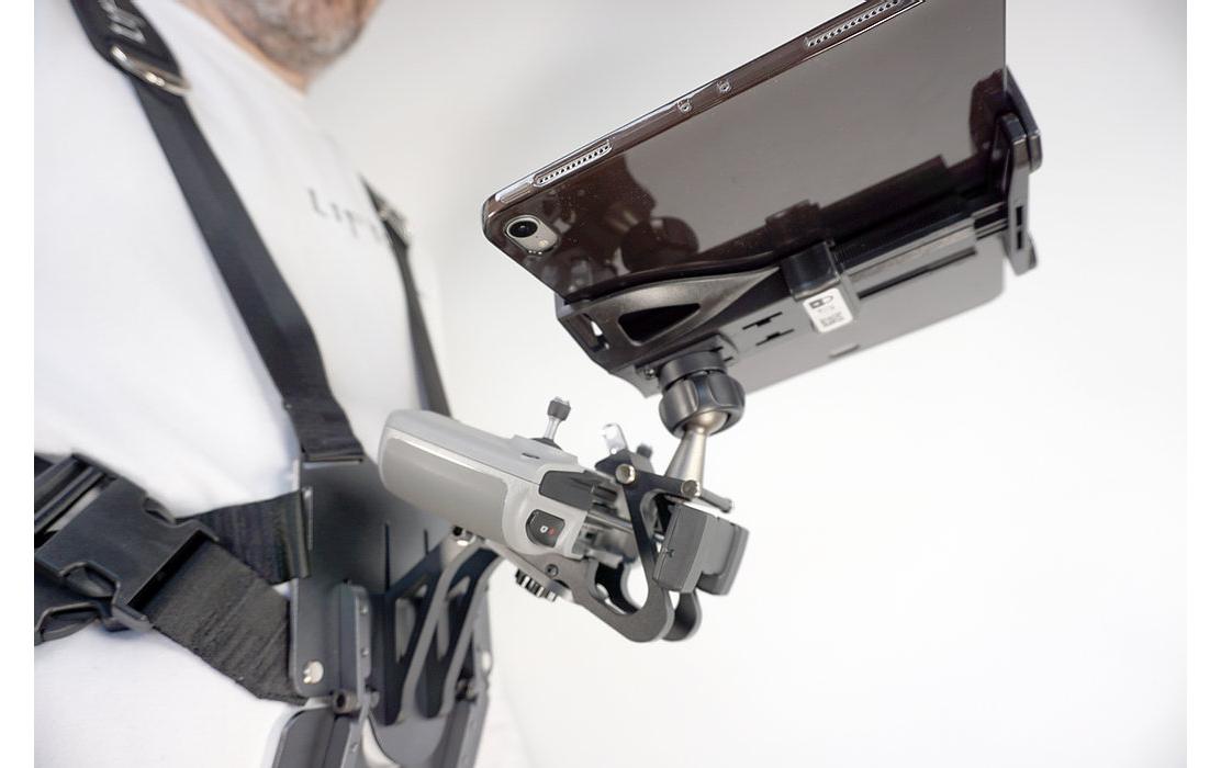 Eine Person in einem weißen Hemd verwendet einen schwarzen LifThor Sendertragegurt StrapThor PRO, um ein Setup mit Kameraausrüstungen, LifThor-Halterungen für ein Tablet und einer kardanisch stabilisierten Kamera zu unterstützen, ideal für Film- oder Fotografie-Enthusiasten.