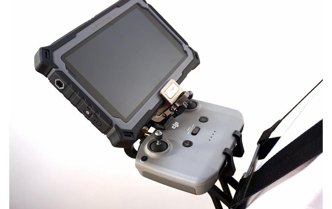 Der LifThor Sendertragegurt StrapThor PRO Drohnencontroller, abgebildet auf weißem Hintergrund, verfügt über einen Bildschirm, zwei Joysticks und mehrere Tasten. Ein befestigter Gurt erleichtert die Handhabung.