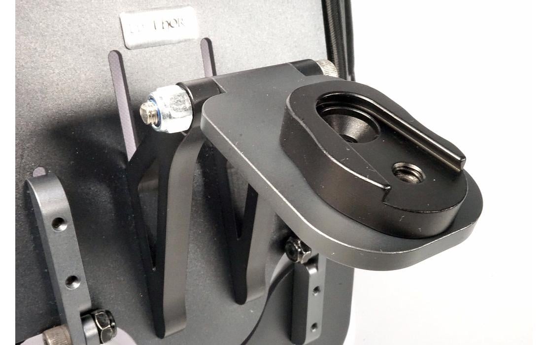 Nahaufnahme des LifThor Sendertragegurts StrapThor PRO mit schwarzer Metallhalterung und runder Befestigungsplatte, wie sie häufig bei Kameraausrüstungen verwendet wird. Das elegante Design besticht durch sichtbare Schrauben und eine strukturierte Oberfläche vor hellem Hintergrund.