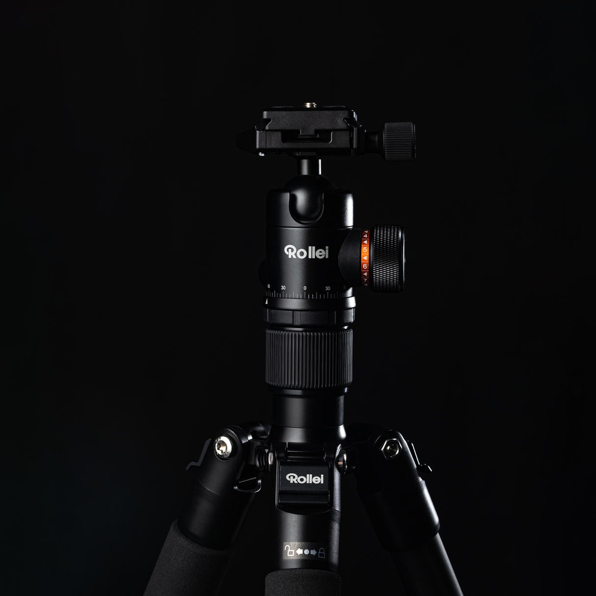 Nahaufnahme eines Stativs Rollei C6i Carbon vor schwarzem Hintergrund. Das robuste Design mit höhenverstellbaren Abschnitten, drehbarem Kopf und Klemme aus langlebigem Carbonmaterial ist deutlich zu erkennen. Der Markenname Rollei ist auf der Hauptsäule deutlich sichtbar.