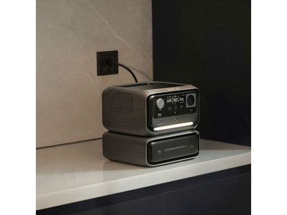 Eine EcoFlow RIVER 3 Max – Powerstation mit 572 Wh / 600 W (X-Boost 1200 W) LiFePO4 von EcoFlow, ausgestattet mit einem übersichtlichen Display und intuitiver Bedienung, steht auf einer Arbeitsplatte und ist an eine Steckdose angeschlossen. Darunter ist ein weiteres Gerät ordentlich gestapelt. Die stilvolle zweifarbige Wand im Hintergrund unterstreicht die kompakte Bauweise und die fortschrittliche LiFePO4-Akkutechnologie.