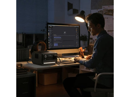 Nachts arbeitet jemand an einem Schreibtisch mit einem Computer, beleuchtet von einer Schreibtischlampe. Auf dem Schreibtisch steht ein EcoFlow RIVER 3 Plus – Powerstation 286 Wh / 600 W (X-Boost 1200 W) LiFePO4 von EcoFlow, dessen zuverlässiger Akku Notstrom liefert, während auf dem Computerbildschirm ein Chat oder eine Programmierplattform zu sehen ist.