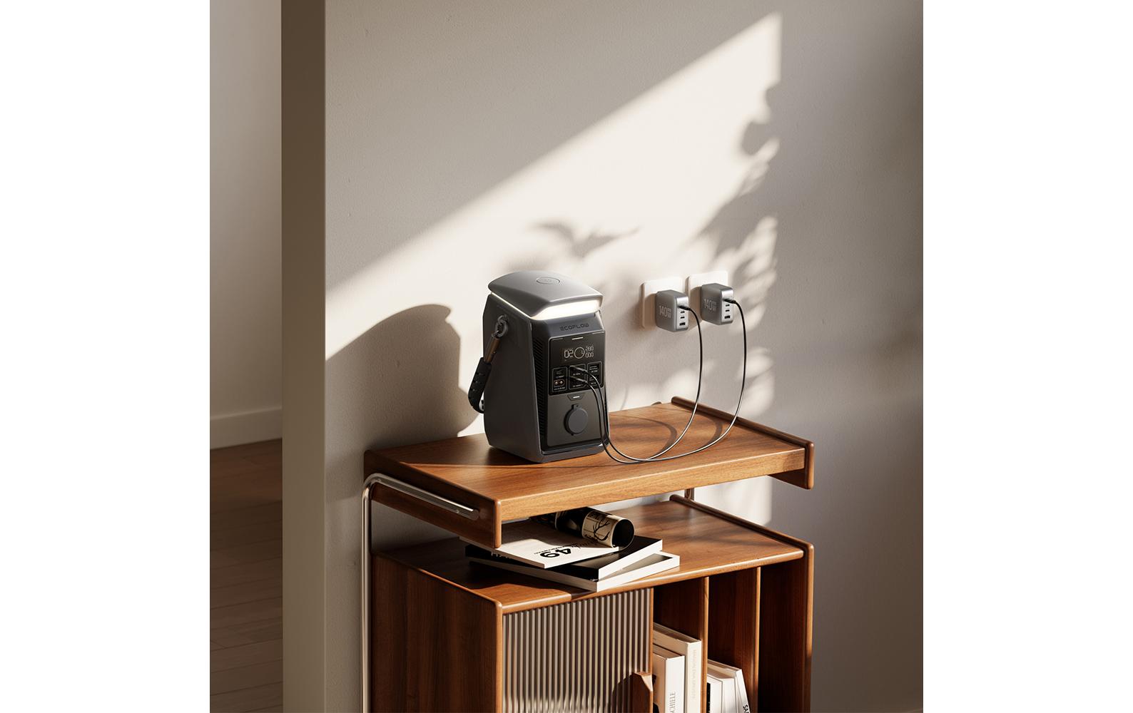 Die EcoFlow TRAIL Plus 300 DC – Powerstation 288 Wh / 300 W (USB-C 140 W) mit Campinglampe von EcoFlow steht auf einem Holzregal und ist über Kabel mit zwei Wandsteckdosen verbunden. Sonnenlicht und Pflanzen Schatten zeichnen Muster an die weiße Wand dahinter. Ideal als mobile Energielösung oder Powerstation fürs Camping – Bücher und Zeitschriften sind ordentlich auf der unteren Ablage angeordnet.