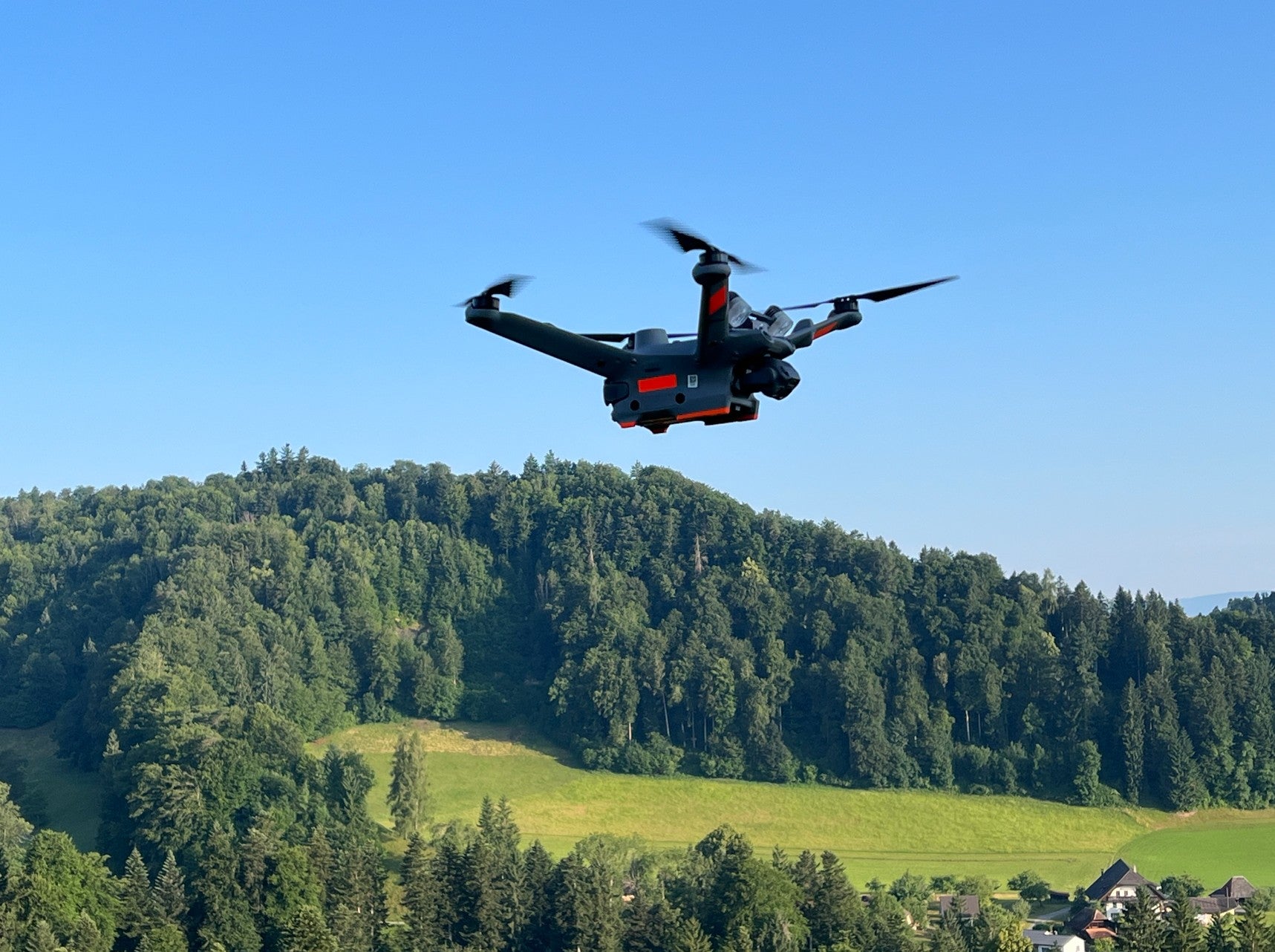 Eine gebrauchte DJI Matrice 3TD von DJI Enterprise (NP: Fr. 11'000.- / VP: Fr. 5'500.-) in sehr gutem Zustand, ideal für Rettungseinsätze mit ihrer robusten IP54-Einstufung, fliegt über eine grüne Landschaft an einem klaren, sonnigen Tag.