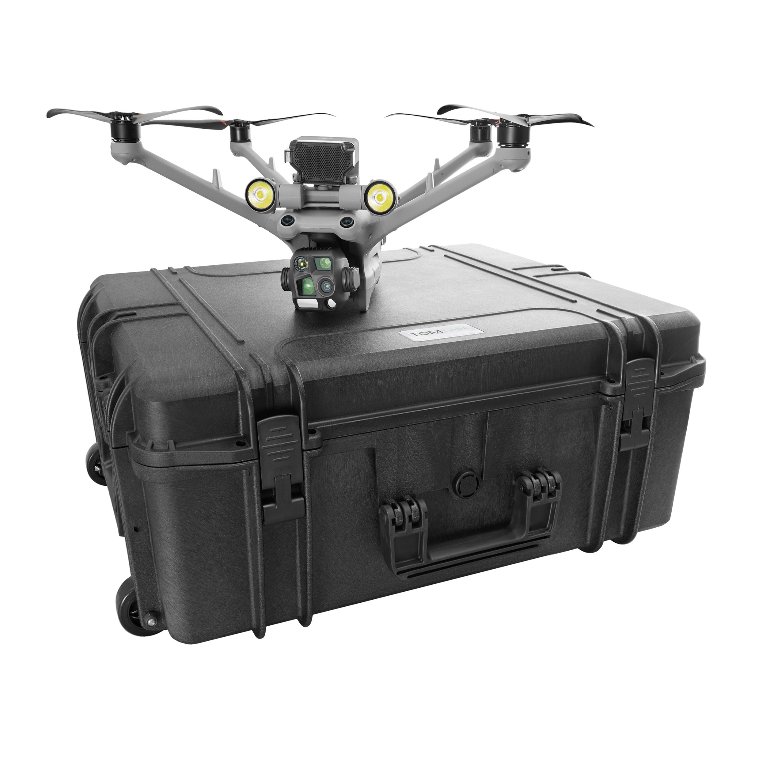 Eine graue, professionelle Industriedrohne, ausgestattet mit Scheinwerfern und mehreren Sensoren, ruht auf einem großen, schwarzen TomCase XT620 „Ready to Fly / Ready to Charge“-Hartschalenkoffer Outdoor-Koffer für DJI Matrice 4D / 4TD (Aufladen im Koffer möglich) von TomCase, der über Rollen und eine robuste Schutzkonstruktion verfügt, vor einem weißen Hintergrund.